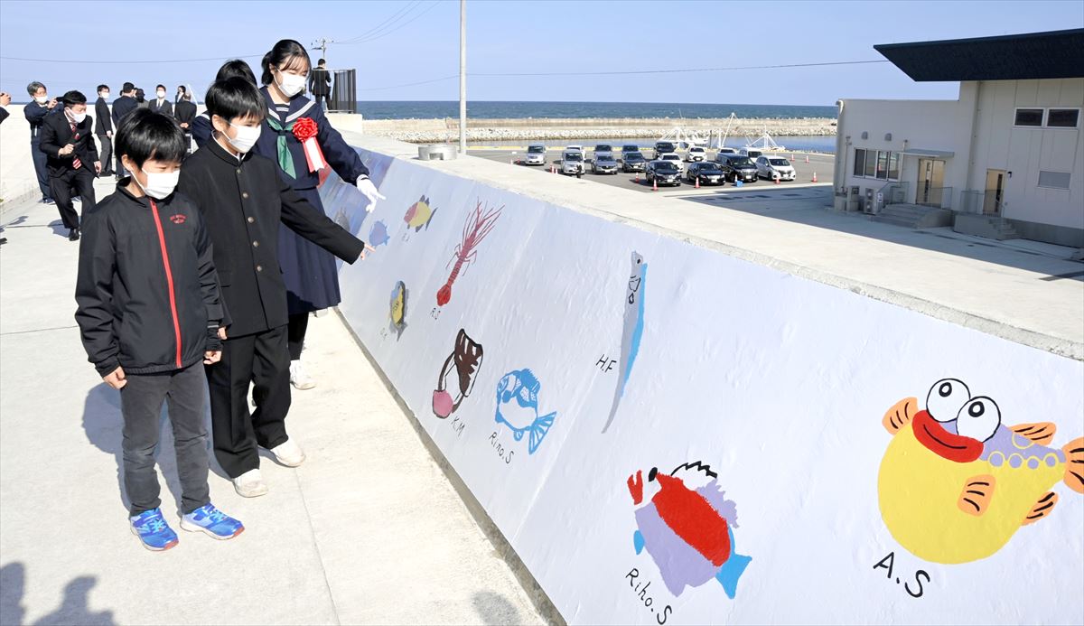 東日本大震災の地震や津波の被害を受けた浪江町の請戸漁港の復旧事業が完了し、20日に現地で竣工式が行われた。地元のなみえ創成小・中の子どもたちが堤防に描いた絵が披露された