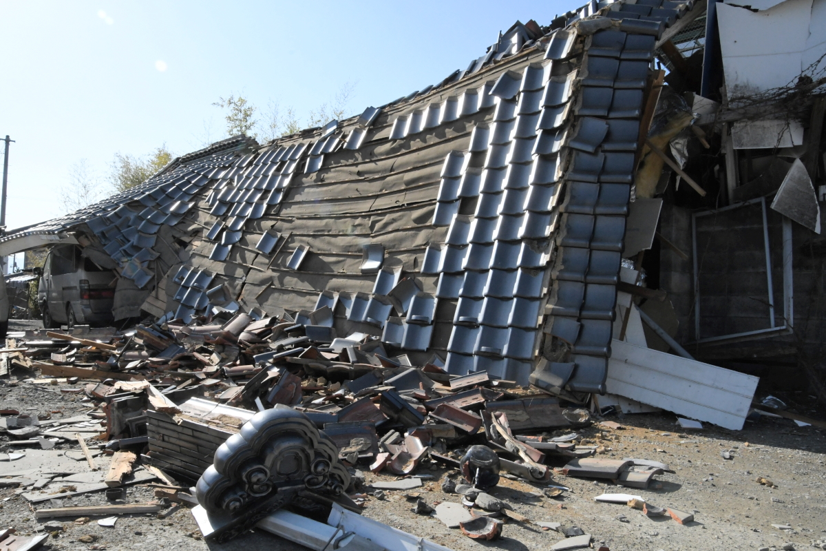 屋根が折れて瓦が散乱した建物=17日午前8時25分ごろ、国見町