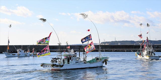 大漁旗をはためかせ、出初めをする漁船