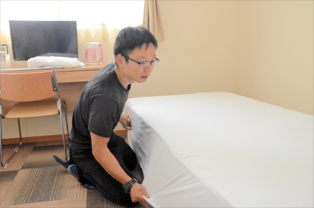 客室のベッドメイキングをする松本さん。手伝いしながら福島の魅力に触れている=福島県楢葉町