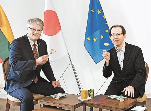 福島市産のモモを一緒に食べる内堀知事(右)とジーカス大使=リトアニア大使館