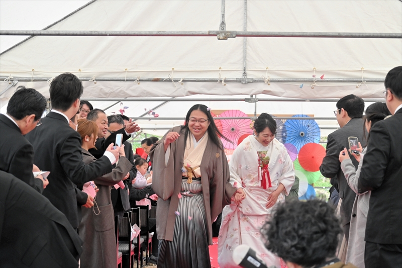 参列者から折り鶴のシャワーを浴びながら退場する渡部さん夫妻