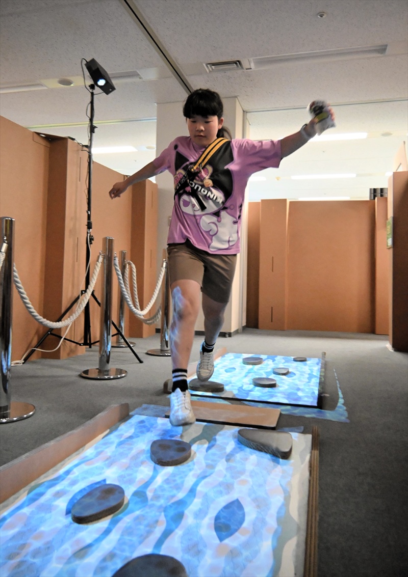 段ボールで作られた飛び石を踏んで渡る来場者