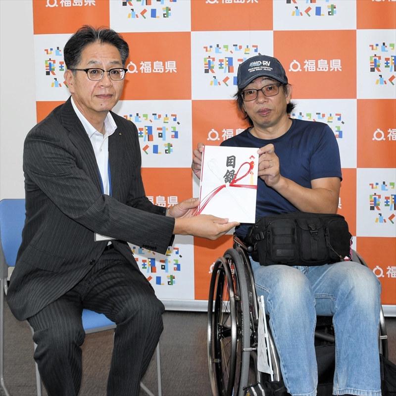 佐藤課長に寄付金を手渡す池田さん(右)