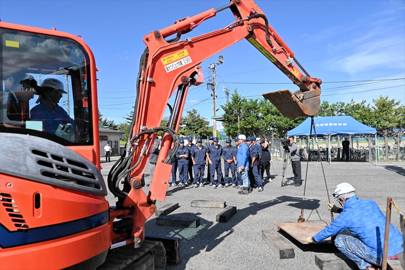 油圧ショベルに乗り、荷物の移動に挑戦する生徒(左)