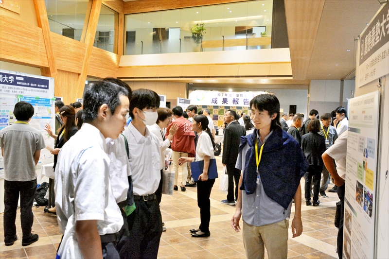 ポスターを掲示し、研究の現状を説明する学生(右)