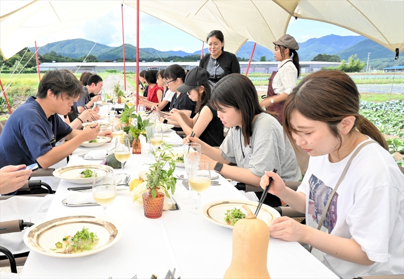 畑に設けられた食事会場で県産食材を使った料理を味わう参加者