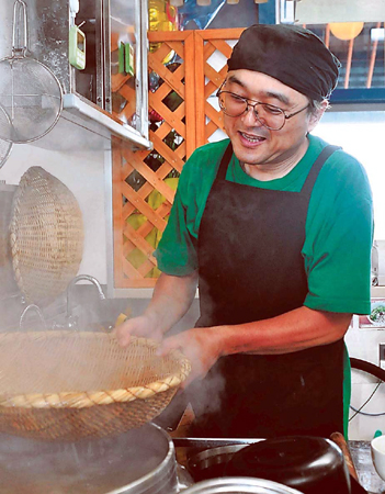 新たな店舗で再出発し、笑顔で調理場に立つ佐藤さん