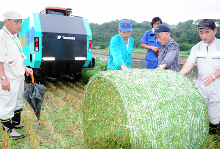 農機で収穫した稲を確認する冨樫代表（右から２人目）らＭＫＦカンパニーの組合員ら