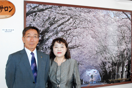 新施設に掲げられた富岡町夜の森地区の〝桜のトンネル〟のパネルと鈴木さん夫婦