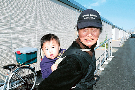 穏やかな表情で近所の子どもおんぶする進さん＝平成２３年１１月