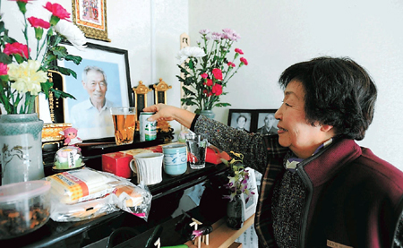 福島市の仮設住宅で夫直延さんの遺影を見詰める近藤さん